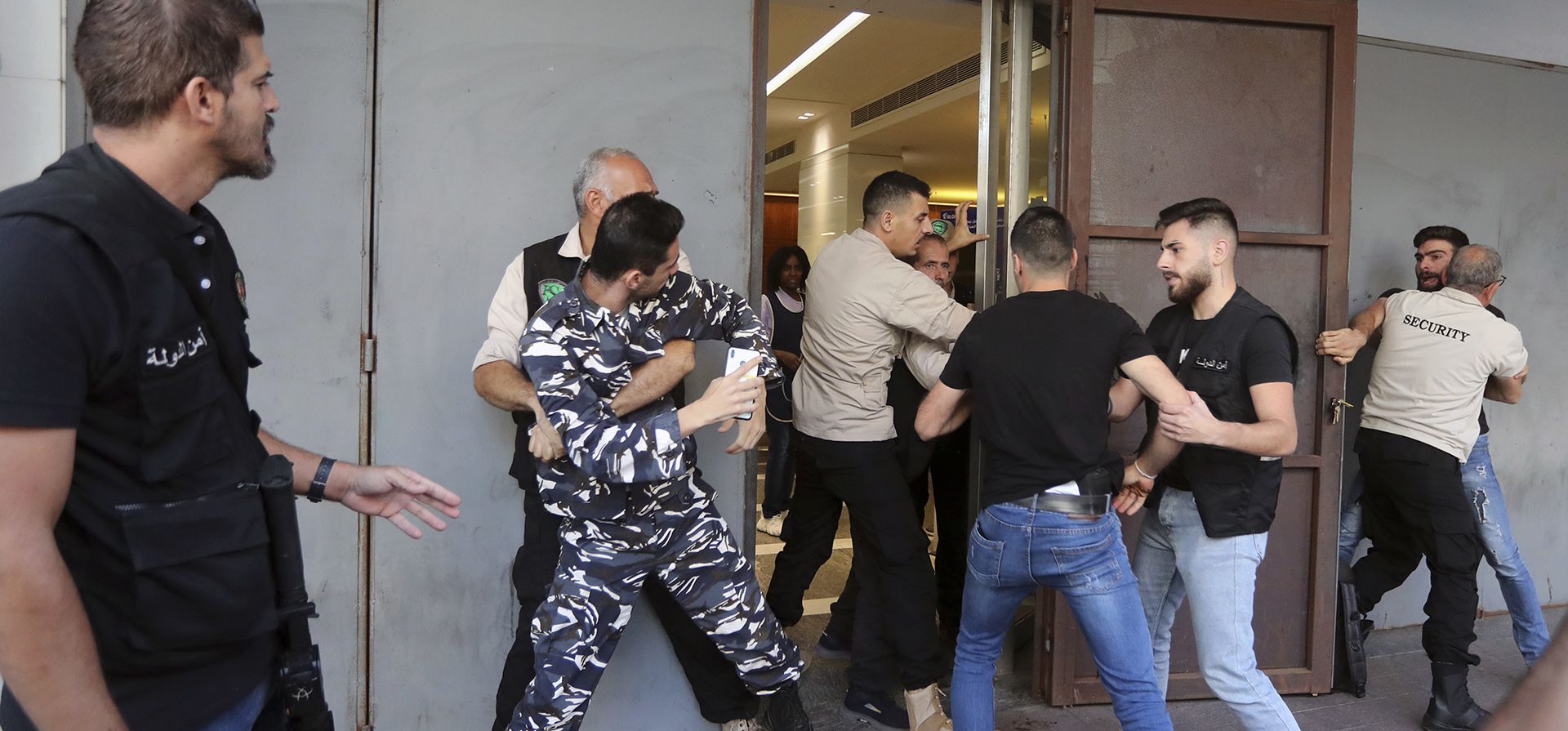 Guardias de seguridad intentan impedir que los miembros del personal de seguridad ingresen a una sucursal del banco BLOM, en la ciudad portuaria sureña de Sidón, Líbano, el lunes 26 de septiembre de 2022. Los bancos libaneses reabrieron parcialmente el lunes luego de un cierre de una semana por temores de seguridad en medio de una ola de atracos y protestas.