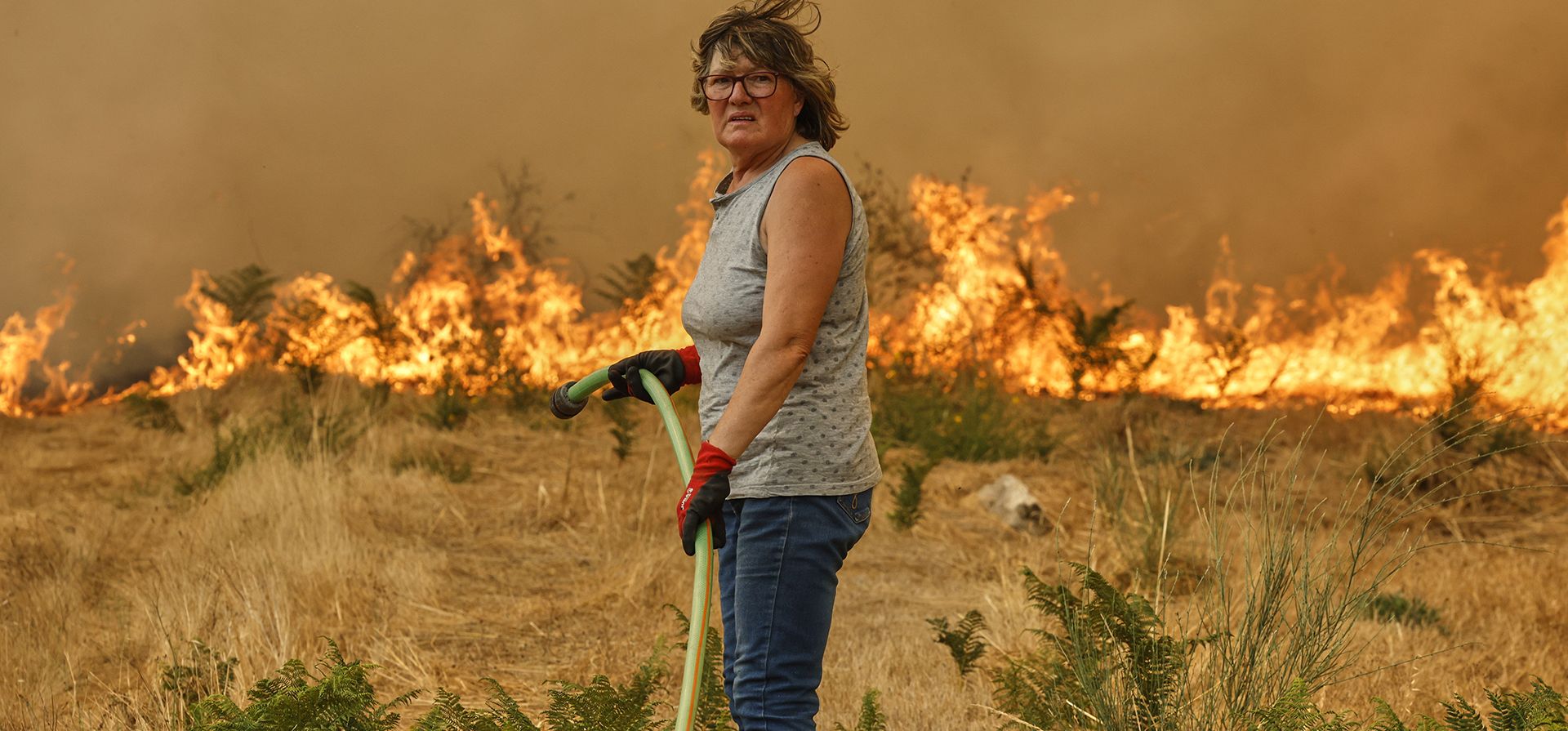 Una mujer con una manguera trata de apagar un incendio en Santa Baia De Montes, en el noroeste de España, el 14 de agosto de 2025. (AP Foto/Lalo R. Villar) Una mujer con una manguera trata de apagar un incendio en Santa Baia De Montes, en el noroeste de España, el 14 de agosto de 2025. (AP Foto/Lalo R. Villar)
