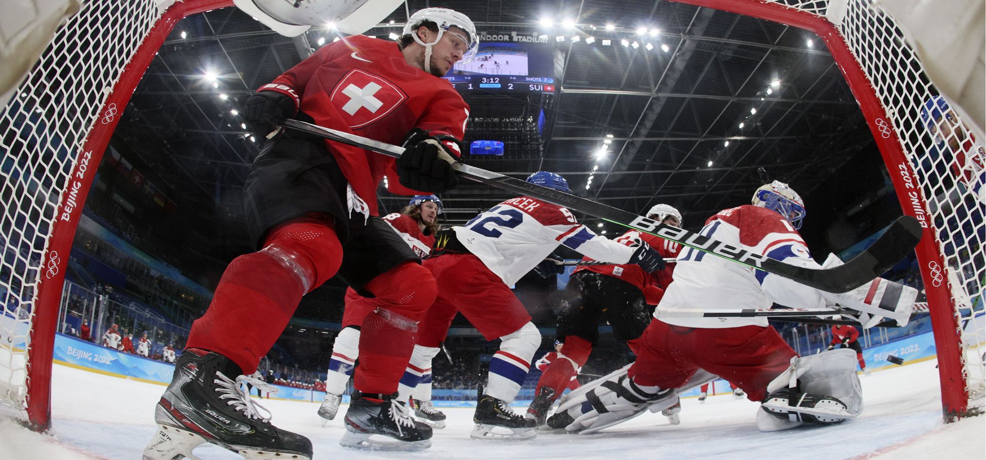 Calvin Thurkauf, de Suiza, a la izquierda, observa cómo el portero de la República Checa, Simon Hrubec (11), bloquea un tiro durante un partido de hockey de la ronda de clasificación masculina en los Juegos Olímpicos de Invierno de 2022, el martes 15 de febrero de 2022 en Beijing.