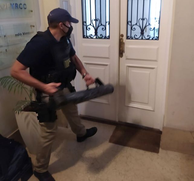 Un efectivo policial intenta violentar el ingreso a la financiera Cofyrco para cumplir con el allanamiento. &nbsp;