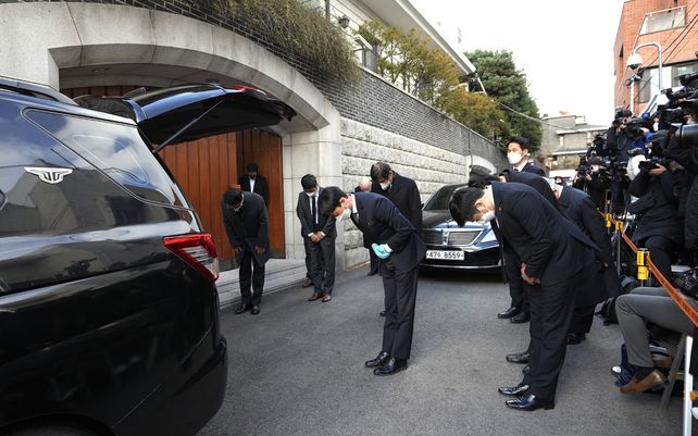 Funcionarios se inclinan cuando un automóvil fúnebre que transporta el cuerpo del ex presidente surcoreano Chun Doo-hwan sale de su casa hacia un salón funerario en Seúl