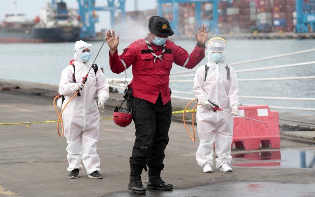 Miembros de la Cruz Roja Indonesia rocían a un socorrista con desinfectante después de clasificar partes de aviones y escombros recuperados del mar de Java, donde un avión Sriwijaya Air se estrelló el sábado, en el puerto de Tanjung Priok en Yakarta, Indonesia.