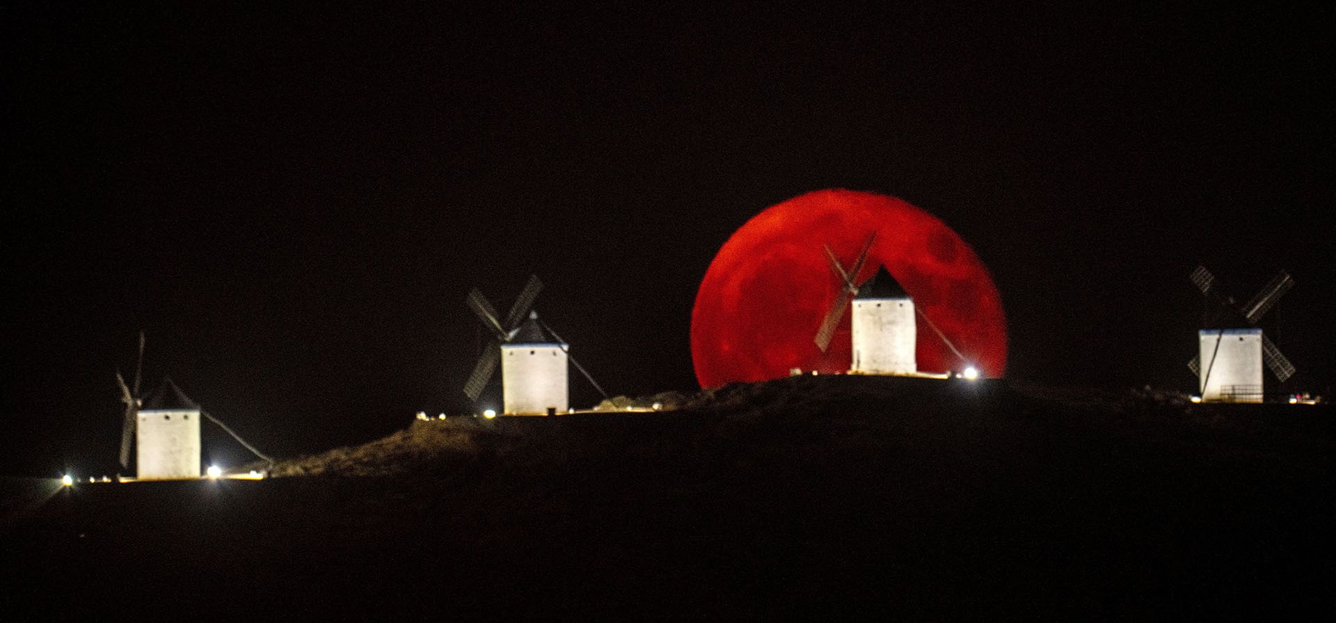 La luna llena se eleva sobre un molino de viento en Consuegra, España.