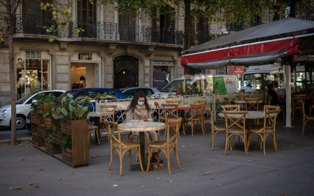 Una mujer sentada en la terraza de un solitario café, en medio del rebrote de coronavirus en el viejo continente, Barcelona, España.