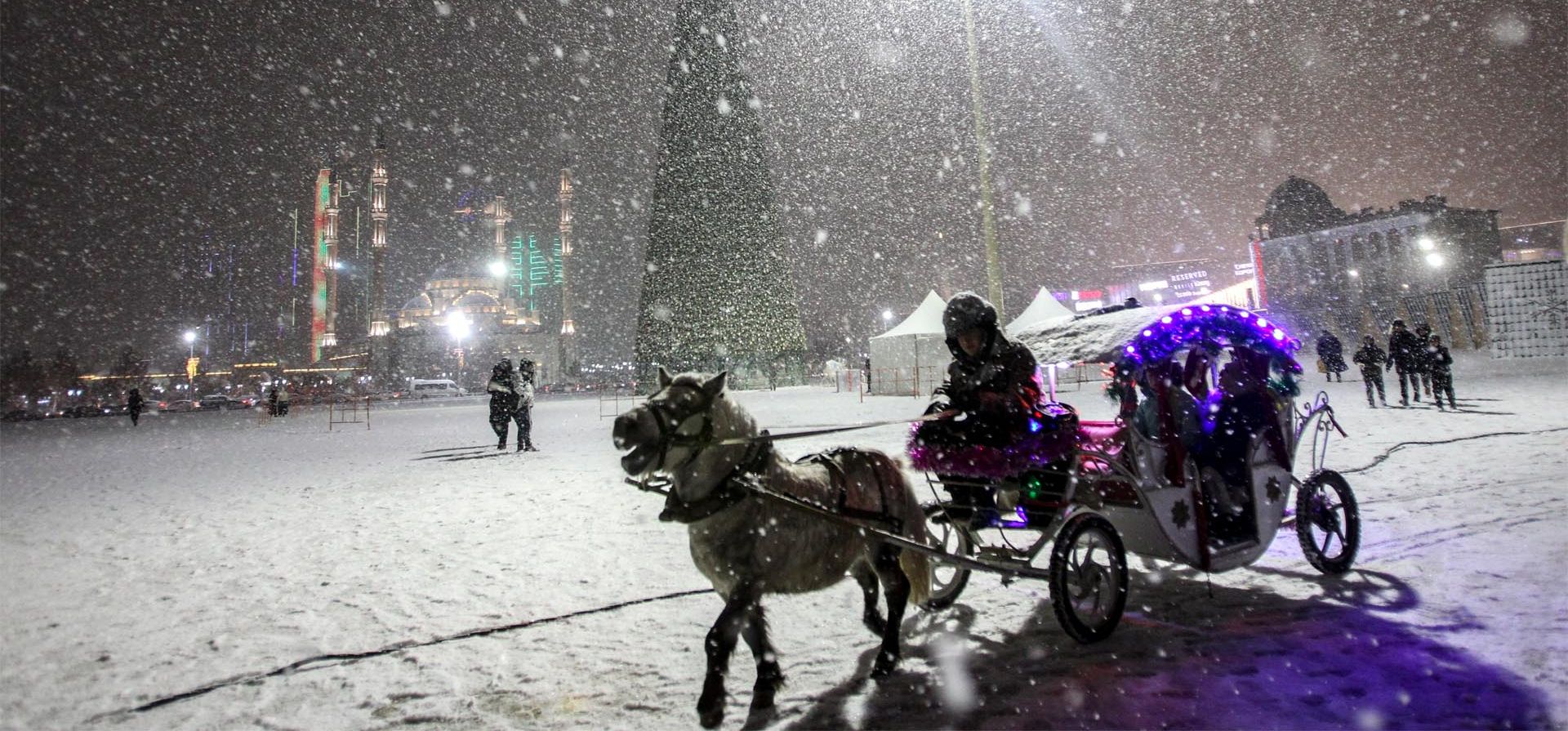 Un hombre monta un pony con niños y pasea por una plaza de Grozny. La gran nevada le da un entorno especial al gran árbol de Navidad preparado para las celebraciones de Año Nuevo, Rusia. Foto: AP