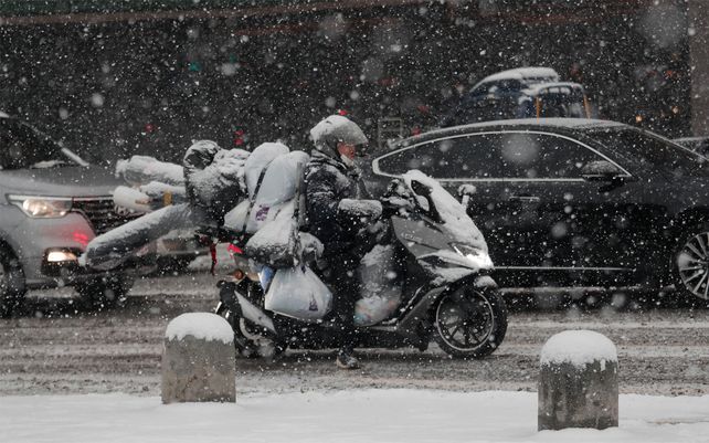Un hombre circula en una motocicleta por las calles de Seúl durante un intenso temporal de nieve.