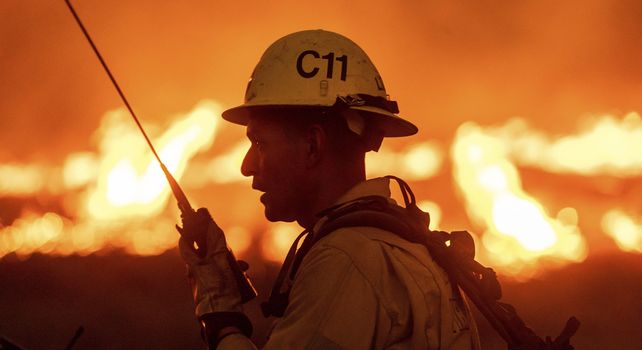 Un bombero se comunica por radio en medio del fuego.