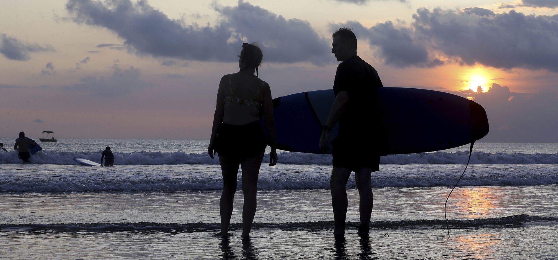 Los turistas observan el océano durante la puesta de sol en la playa de Kuta en Bali, Indonesia, el lunes 16 de mayo de 2022.