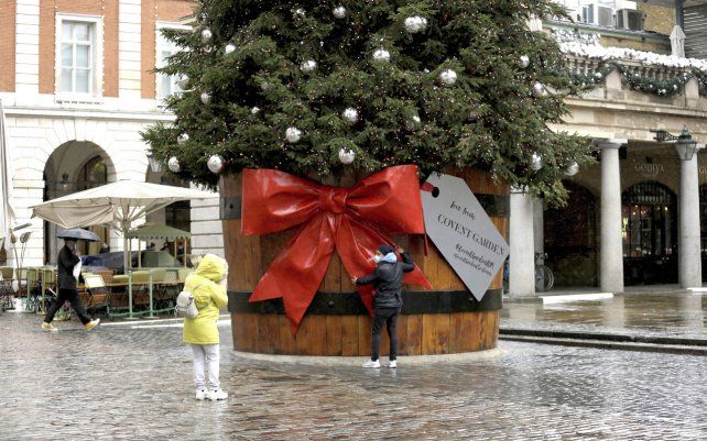 Una mujer se toma una foto con un árbol de Navidad en el área de Covent Garden de Londres, durante el segundo encierro por coronavirus en Inglaterra.