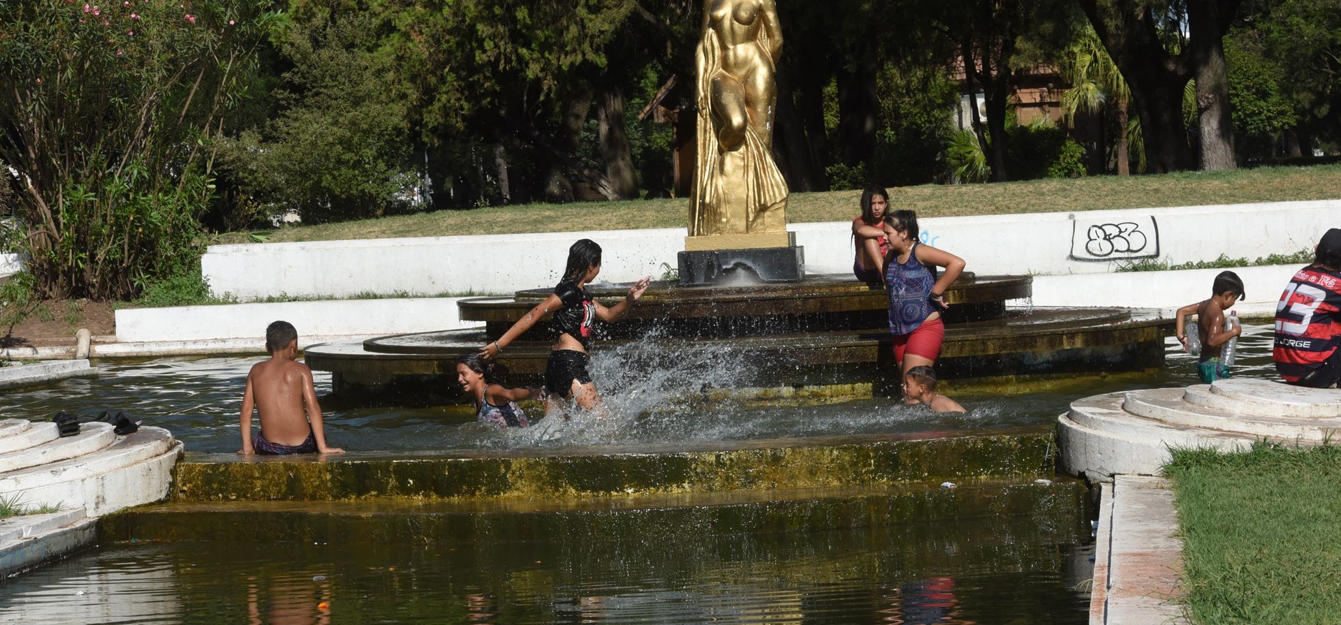 Un grupo de niños se refresca en una de las fuentes del Parque Independencia.