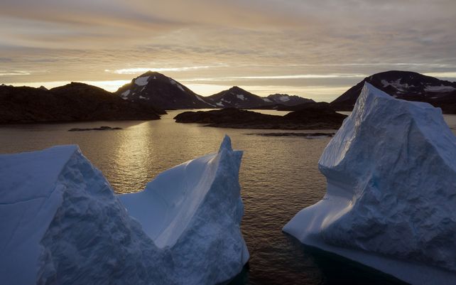 Una vista aérea de grandes icebergs flotando mientras el sol sale cerca de Kulusuk