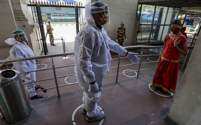 Un guardia de seguridad con traje protector controla la entrada a un visitante del Museo Indio