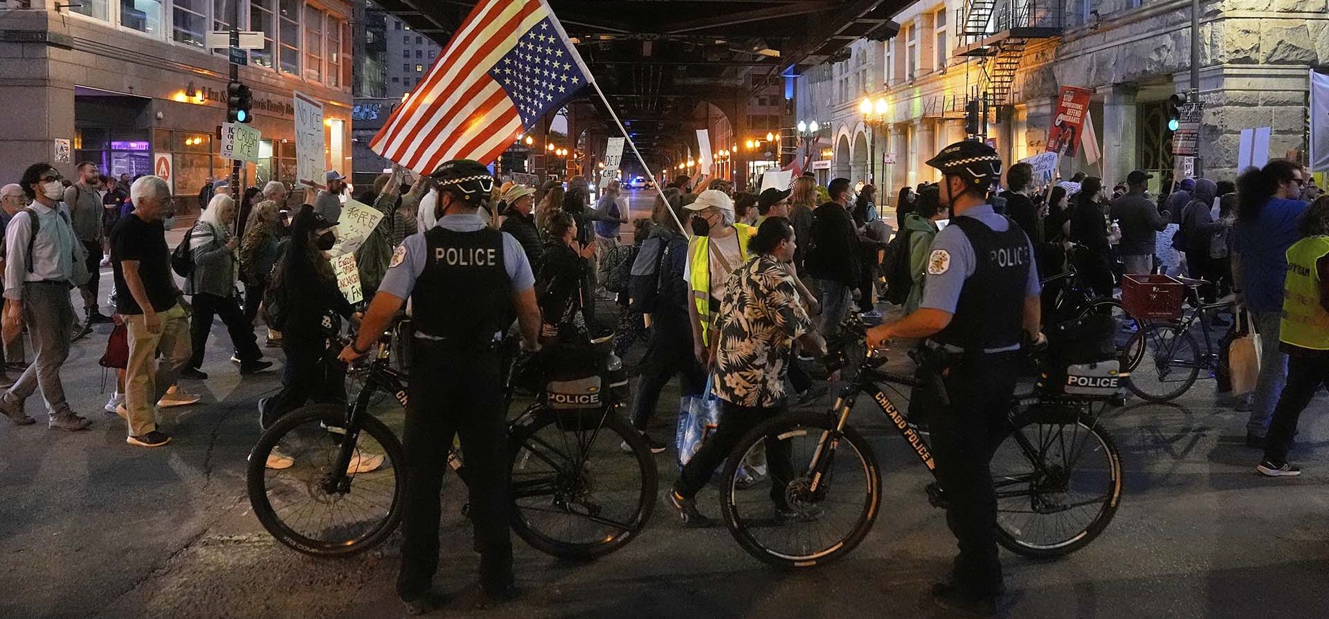 Agentes de policía bloquean una calle mientras manifestantes marchan en una protesta contra la Agentes de policía bloquean una calle mientras manifestantes marchan en una protesta contra la