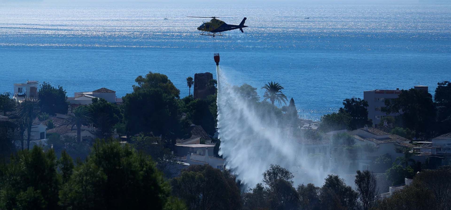 Un helicóptero de extinción de incendios esparce agua sobre un incendio forestal en la ciudad costera de Benalmádena, en la Costa del Sol, Benalmádena, España. Fotografía: Jorge Zapata/EPA Un helicóptero de extinción de incendios esparce agua sobre un incendio forestal en la ciudad costera de Benalmádena, en la Costa del Sol, Benalmádena, España. Fotografía: Jorge Zapata/EPA