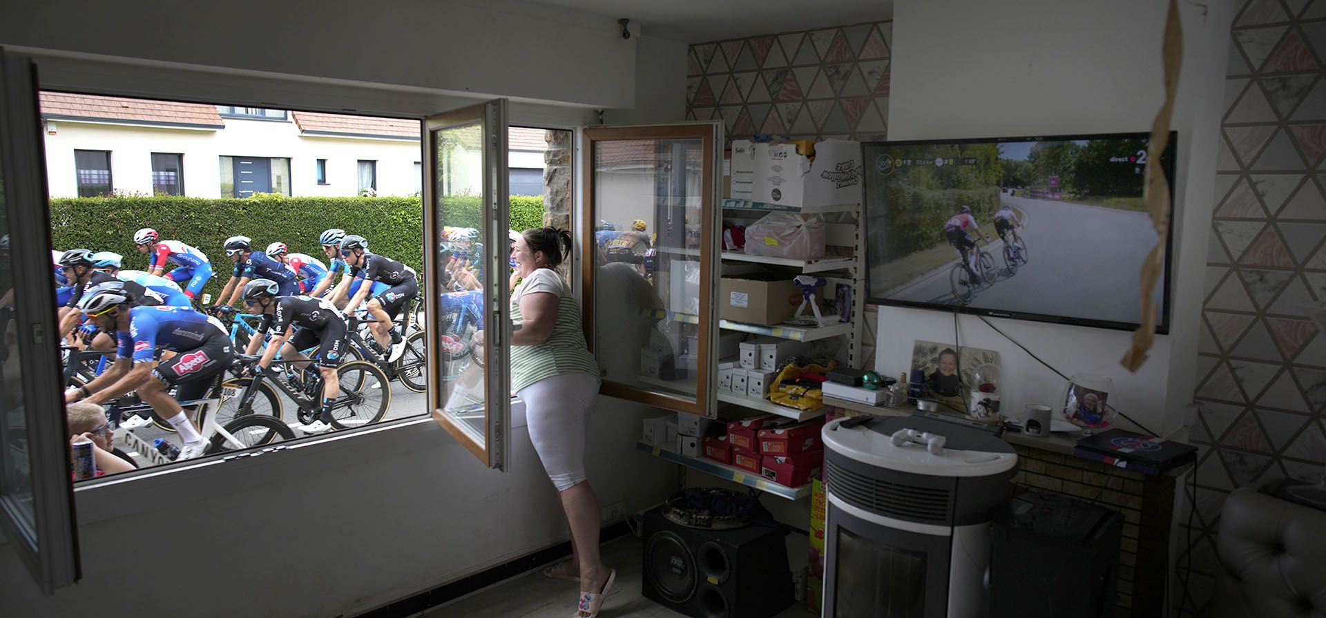 Una mujer anima a un pelotón de ciclistas, de pie junto a su ventana, durante el Tour de Francia de 171,5 kilómetros con inicio en Dunkerque y final en Calais, Francia.