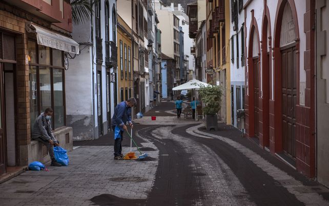 Residentes limpian las cenizas de una calle en Santa Cruz de la Palma en la isla canaria de La Palma, España, el lunes 27 de septiembre de 2021. Una enorme nube de ceniza impidió los vuelos dentro y fuera de la isla española de La Palma.