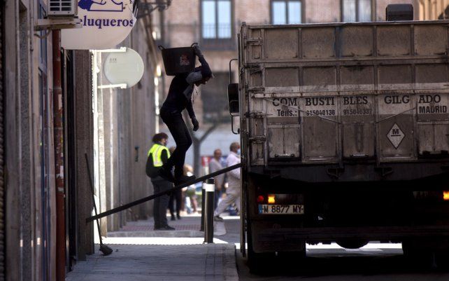 Un trabajador camina sobre una tabla hacia un camión mientras saca los residuos de escombros de un edificio en Madrid, España.