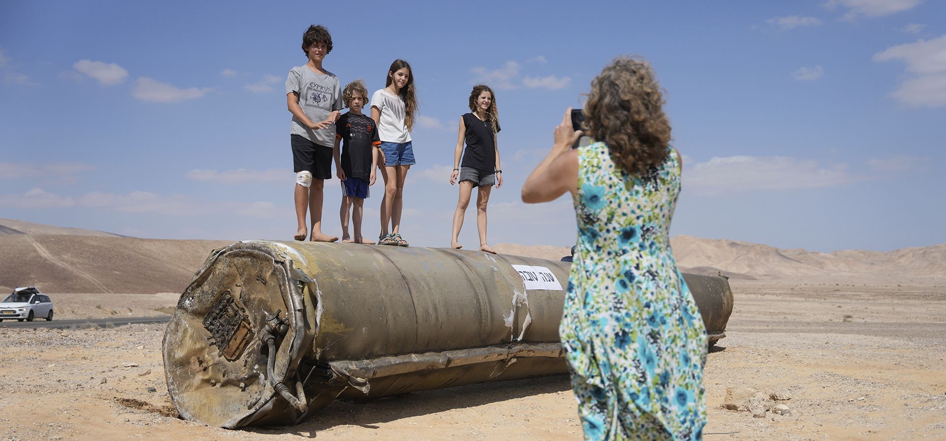 Una mujer toma fotografías de sus hijos con los restos de un misil iraní interceptado por Israel, cerca de Arad, en el sur de Israel, el 2 de octubre de 2024. (Foto AP/Ohad Zwigenberg)