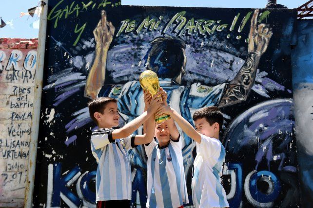 De otra galaxia y de mi barrio. Atrás un reconocimiento a Messi en un mural mientras los chicos juegan a levantar la copa.