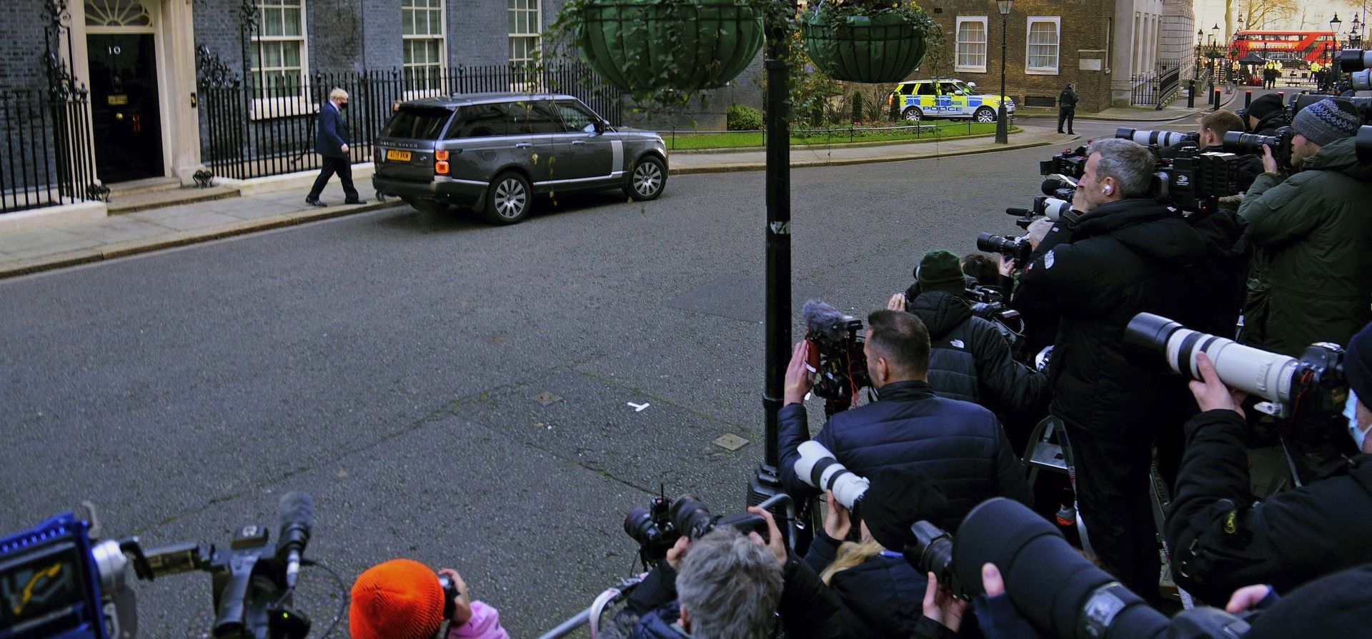 Fotógrafos y periodistas de medios televisivos capturan la salida del primer ministro británico Boris Johnson de su residencia del número 10 de Downing Street, Londres, para asistir a las preguntas del primer ministro en las Casas del Parlamento, en Londres, el miércoles 19 de enero de 2022.