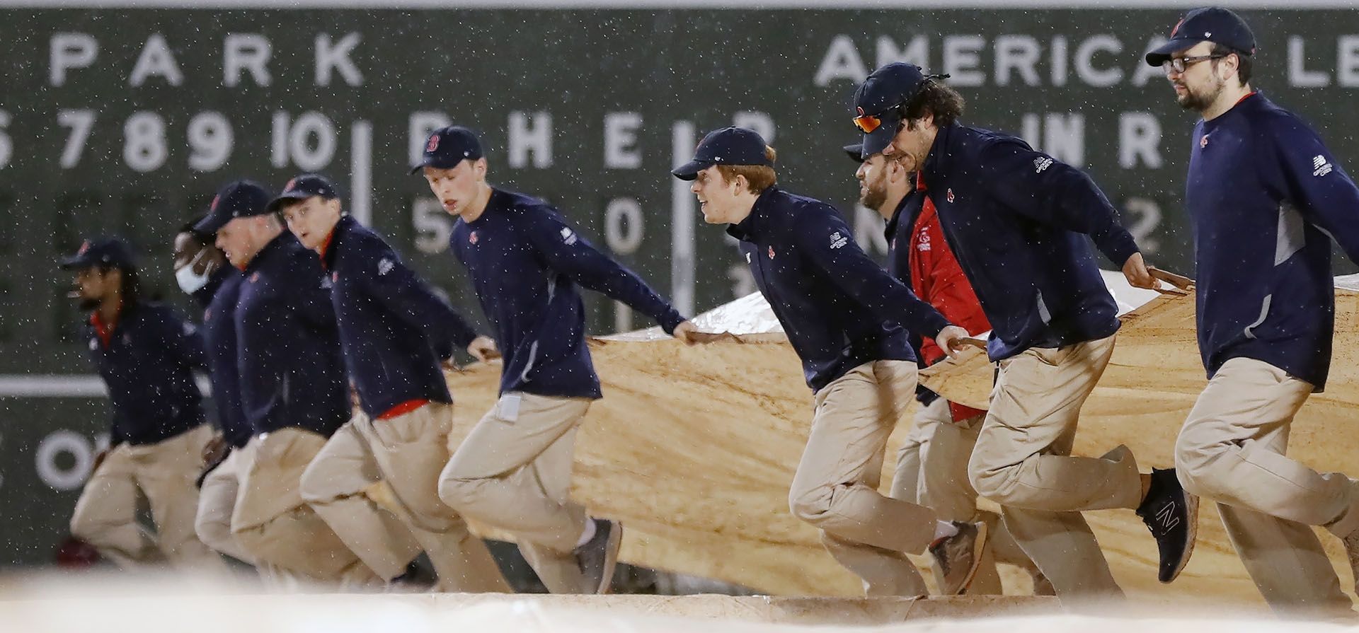 El personal de mantenimiento del Fenway Park saca la lona durante el tercer inning de un partido de béisbol entre los Medias Rojas de Boston y los Orioles de Baltimore, el lunes 26 de septiembre de 2022, en Boston.