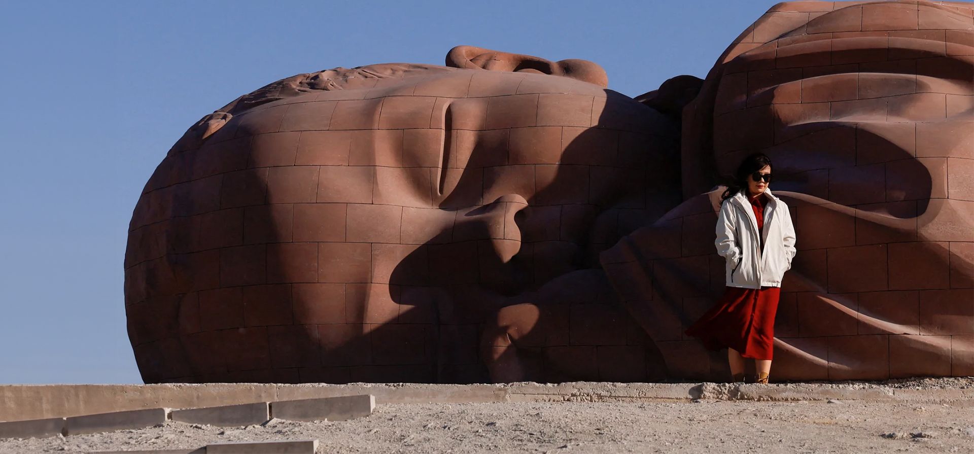 Un turista en la enorme escultura del bebé dormido Hijo de la Tierra en la provincia de Gansu, en el desierto de Gobi, Guazhou, China. Fotografía: Tingshu Wang/Reuters Un turista en la enorme escultura del bebé dormido Hijo de la Tierra en la provincia de Gansu, en el desierto de Gobi, Guazhou, China. Fotografía: Tingshu Wang/Reuters