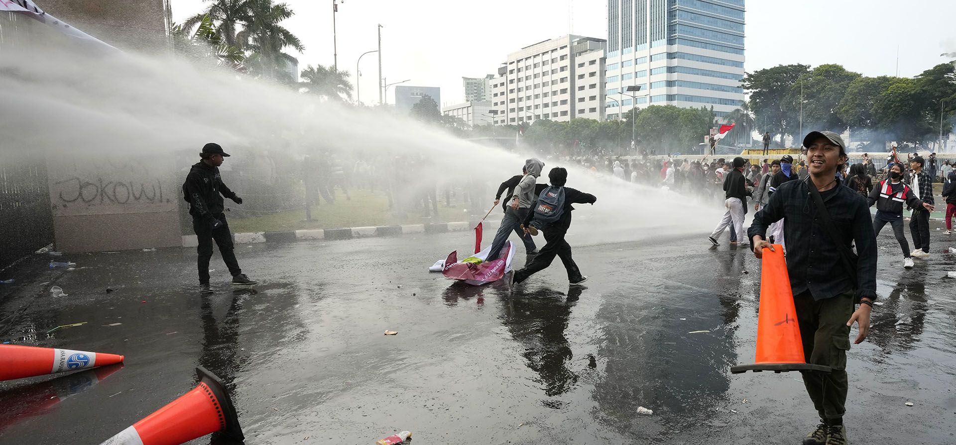 Manifestantes huyen mientras la policía usa un cañón de agua para dispersarlos durante una manifestación frente al parlamento en Yakarta, Indonesia, el lunes 11 de abril de 2022. Miles de estudiantes marcharon el lunes en ciudades de Indonesia para protestar contra los rumores de que el gobierno está considerando posponer la elecciones presidenciales de 2024 para permitir que el presidente Joko Widodo permanezca en el cargo más allá del límite legal de dos mandatos.