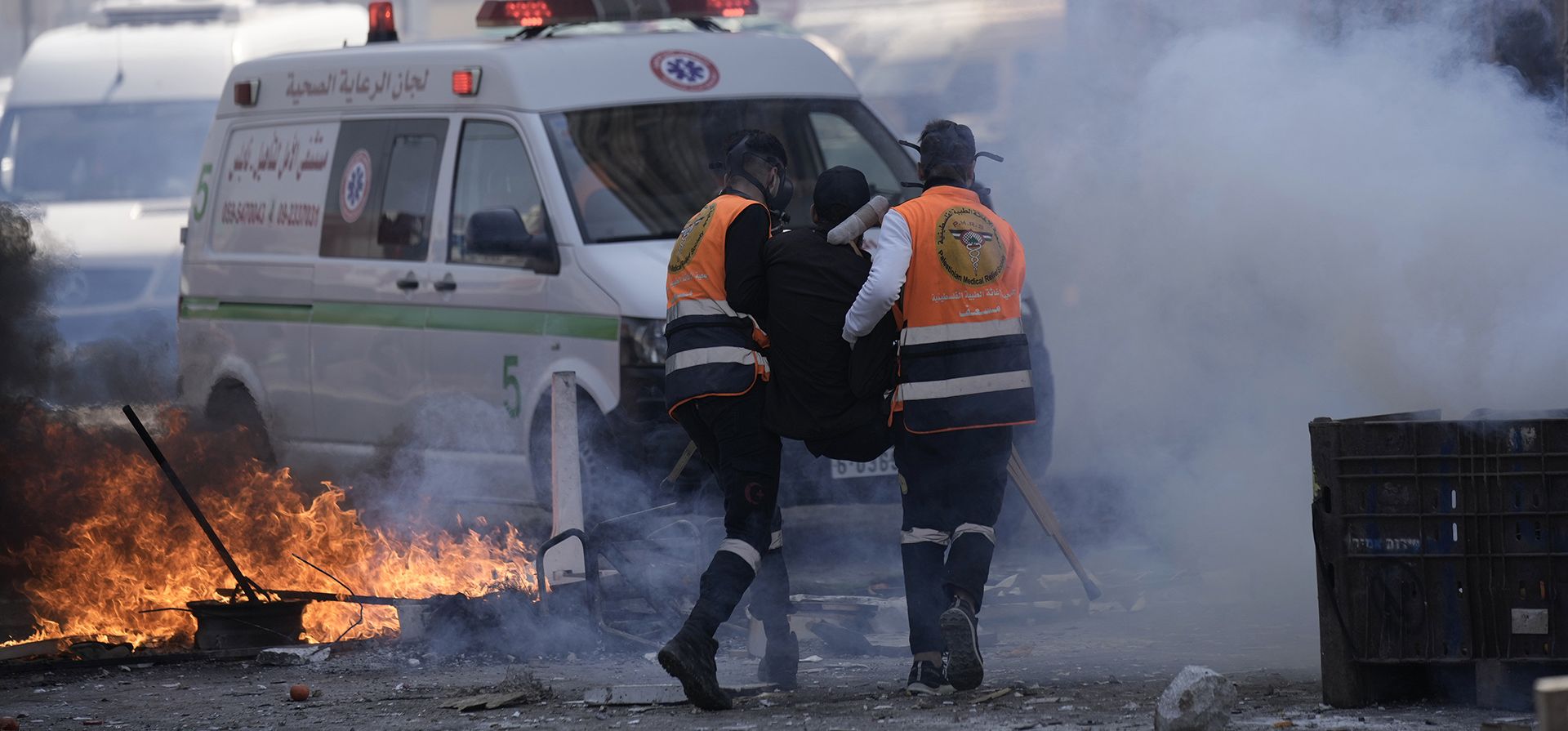 Personal médico corren a través de gases lacrimógenos mientras evacuan a un palestino herido durante los enfrentamientos con las fuerzas israelíes en la ciudad de Naplusa, Cisjordania, el miércoles 22 de febrero de 2023. (Foto AP/Majdi Mohamed)