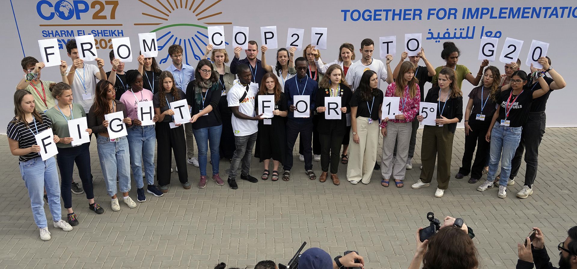 Jóvenes activistas sostienen carteles que dicen "de la COP27 al G20 luchan por 1.5" en la Cumbre Climática de la ONU COP27, el lunes 14 de noviembre de 2022, en Sharm el-Sheikh, Egipto.