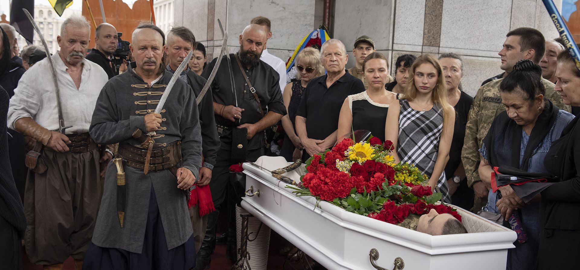Familiares y amigos asisten al funeral de los oficiales Andriy Zhovanyk y Yuri Kovalenko, que murieron en una batalla contra las tropas rusas, en la céntrica plaza de la Independencia en Kyiv, Ucrania, el viernes 5 de agosto de 2022. Una guardia de honor vestida como cosacos presenta su respeto a la familia.