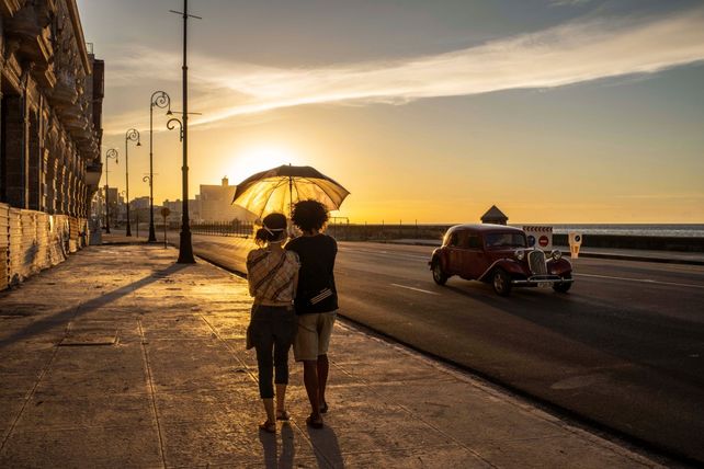 Una pareja usando barbijo como precaución camina por el Malecón.