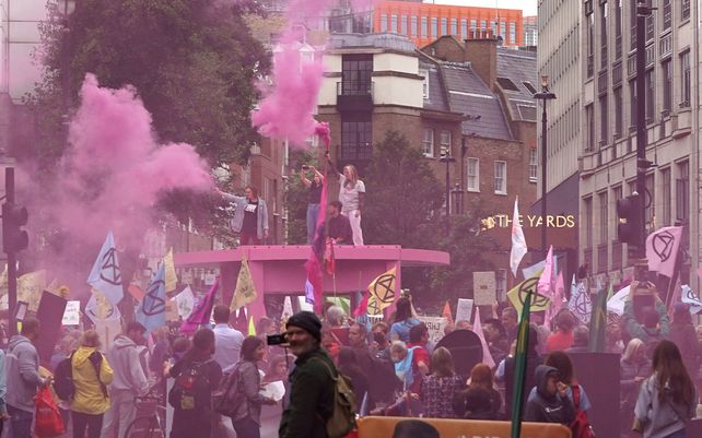 Activistas ambientales del grupo Extinction Rebellion envueltos en humo se manifiestan en Trafalgar Square