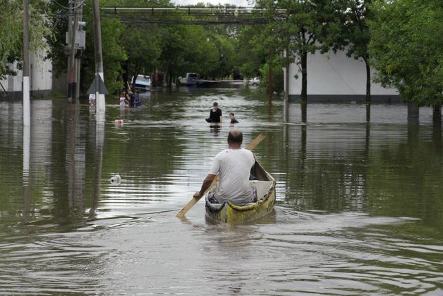 Un vecino rema en una canoa para poder desplazarse de su casa hacia otros lugares y brindar ayuda.