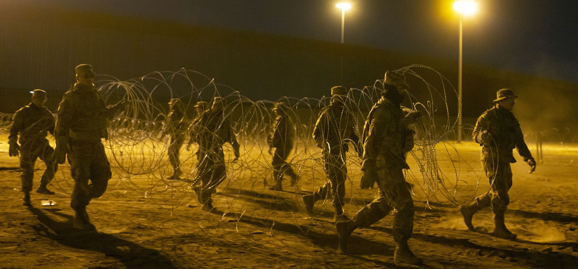Soldados de la Guardia Nacional de Texas llevan alambre de púas para instalarlo cerca de una puerta en la valla fronteriza en El Paso, Texas, en la madrugada del jueves 11 de mayo de 2023. Los migrantes cruzaron la frontera horas antes de que se aplicaran las restricciones de asilo relacionadas con la pandemia, expirará el jueves, por temor a que las nuevas políticas dificulten mucho más la entrada a Estados Unidos. (Foto AP/Andrés Leighton)