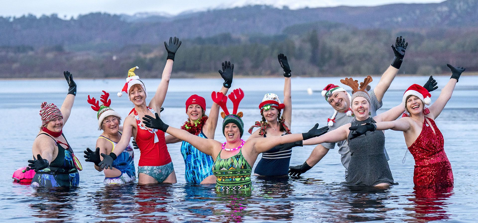 Miembros del grupo de natación salvaje Loch Insh Dippers participan en un nado con temática navideña en Loch Insh en el Parque Nacional Cairngorms cerca de Aviemore, Escocia, el viernes 23 de diciembre de 2022. (Jane Barlow/PA vía AP)