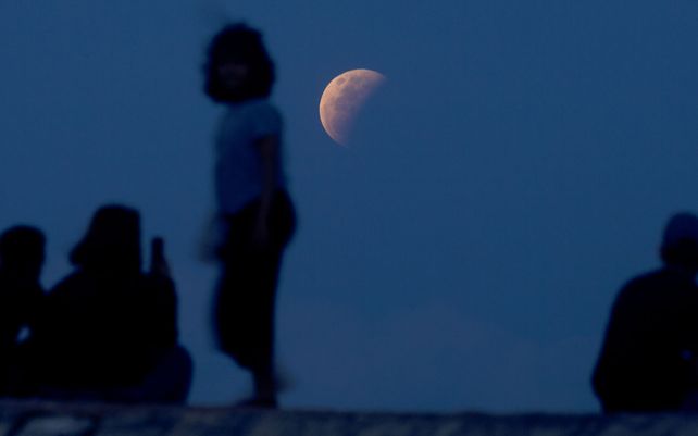 Los residentes ven el eclipse lunar en la playa de Sanur en Bali