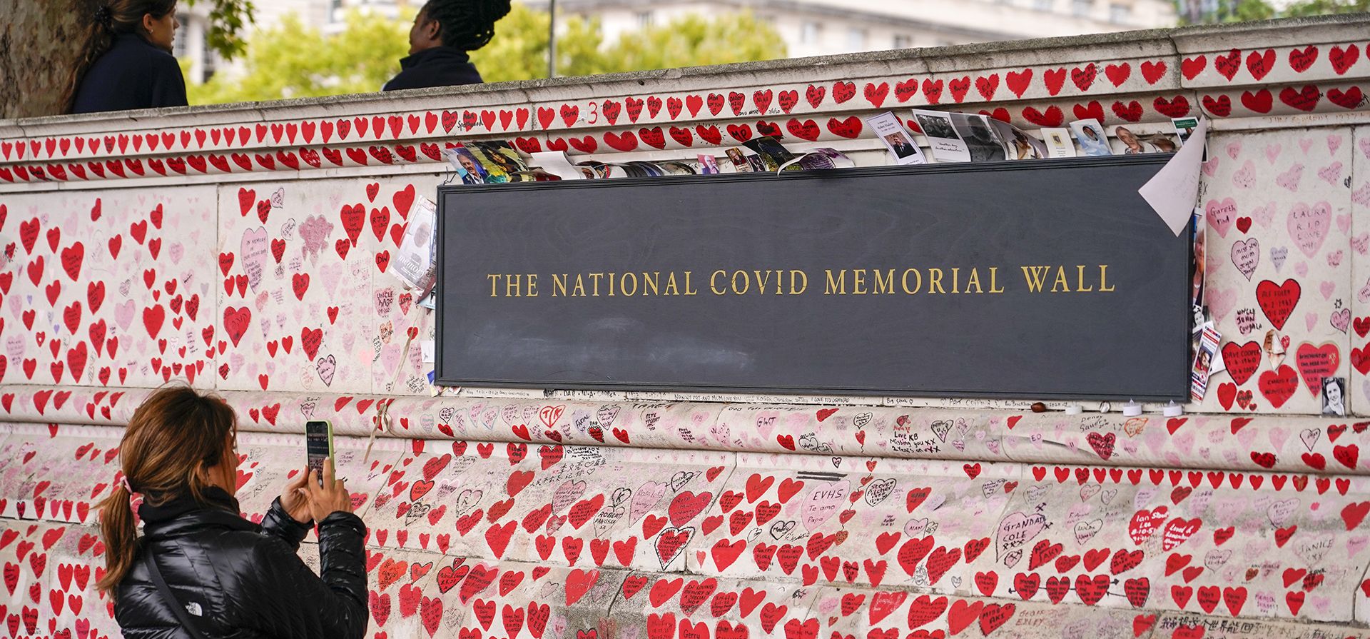 Una mujer toma una fotografía del Muro Conmemorativo Nacional de Covid, en la orilla sur del río Támesis, en Londres, el martes 4 de octubre de 2022. La investigación pública sobre la respuesta del Reino Unido a la pandemia de Covid-19 y su impacto ha comenzó en Londres.