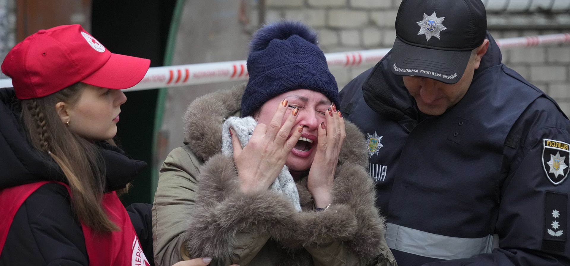 Una mujer es consolada por militares mientras llora en la escena del bombardeo nocturno en Mykolaiv, Ucrania, el viernes 11 de noviembre de 2022.