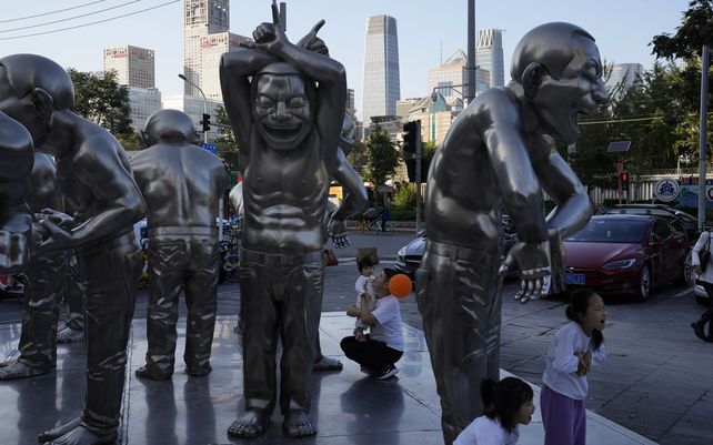 Residentes juegan entre esculturas afuera de una galería de exhibición en Beijing el jueves 7 de octubre de 2021. A medida que el feriado del día nacional de una semana llega a su fin, los residentes se toman un descanso del clima lluvioso para salir.
