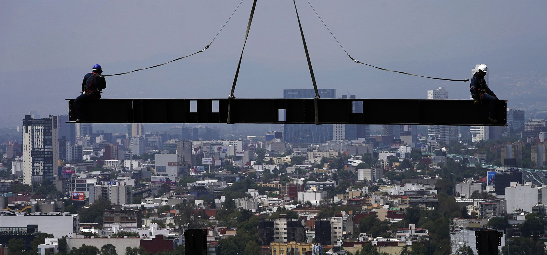 Trabajadores de la construcción trabajan sobre una viga que cuelga de una grúa en el sitio de construcción de un edificio residencial de gran altura en la Ciudad de México, el viernes 24 de junio de 2022.