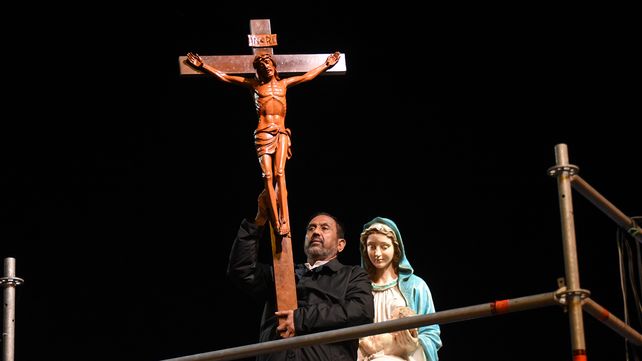 El Padre Ignacio sostiene la cruz dando la bendición a los enfermos sobre el final del Via Crucis de barrio Rucci.