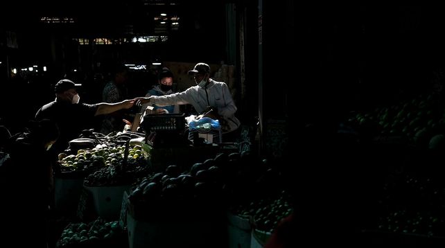 Un vendedor saluda con el puño en el mercado La Vega de la capital chilena