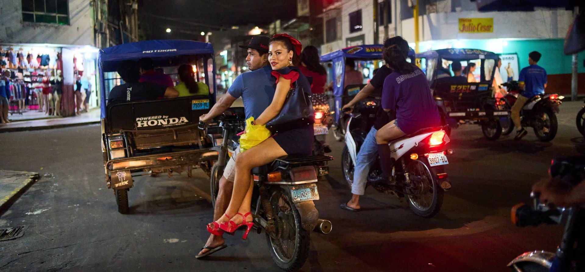 Una mujer se sienta de lado detrás de su amiga en una motocicleta, Iquitos, Perú. Fotografía: Rodrigo Abd/AP Una mujer se sienta de lado detrás de su amiga en una motocicleta, Iquitos, Perú. Fotografía: Rodrigo Abd/AP