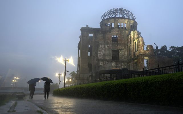 Transeúntes caminan bajo una fuerte lluvia cerca de la Cúpula de la Bomba Atómica en Hiroshima