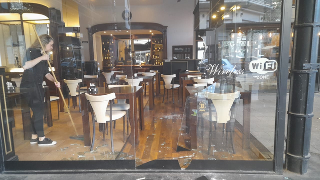 Una empleada del bar de Maipú y Córdoba barre los vidrios que quedaron en el piso tras el impacto de un piedrazo.