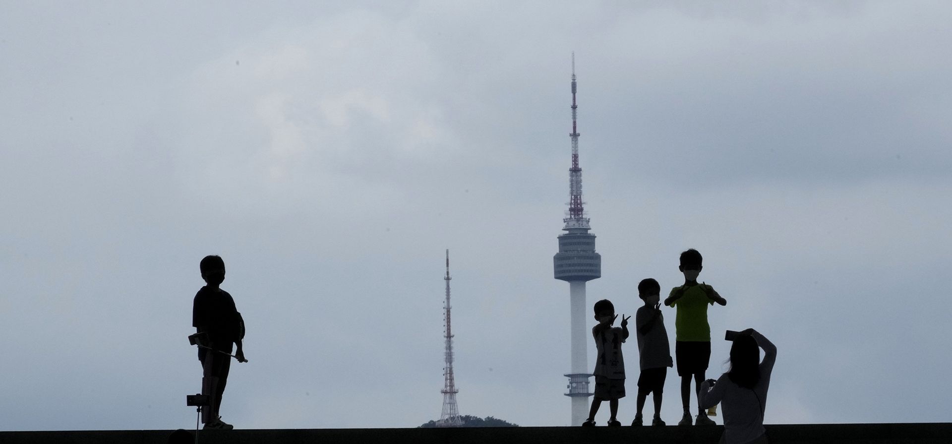 Los niños posan mientras la madre toma fotografías con el fondo de la icónica Torre N de Seúl en el Museo Nacional de Corea en Seúl, Corea del Sur, el lunes 1 de agosto de 2022. 