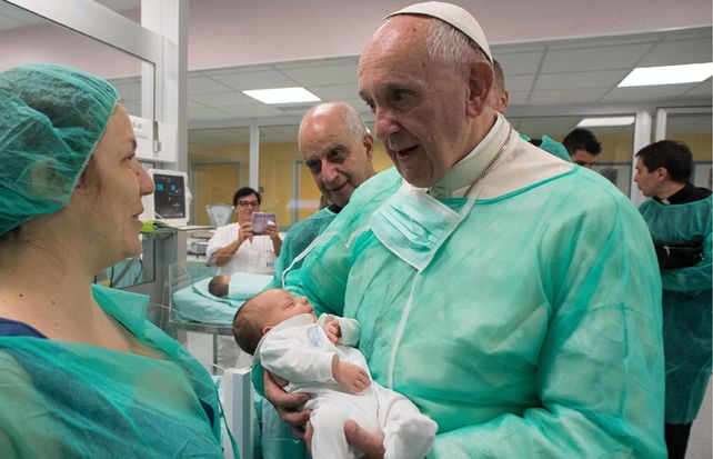 Consuelo. Francisco sostiene a un bebé en el Hospital San Giovanni.