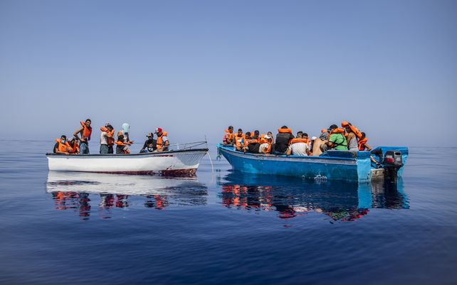 Un grupo de migrantes de Túnez a bordo de precarias embarcaciones de madera espera ser asistido por un equipo de la ONG española Open Arms