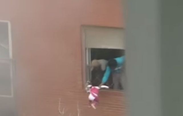 Los padres arrojan a la pequeña de tres años en un intento desesperado por salvarla de las llamas.