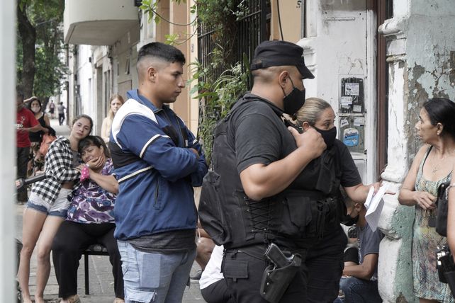 La madre de Melani observa sentada el trabajo de los policías en la puerta de la pensión.